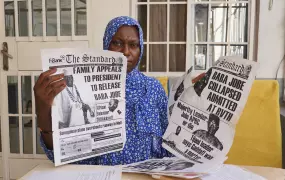 ¡Tida Baba Jobe holds up newspaper clippings of her husband, who was executed by Yahya Jammeh’s regime in 2011. She is frustrated that Jammah associates have received jobs in government, while her family struggles financially and psychologically.